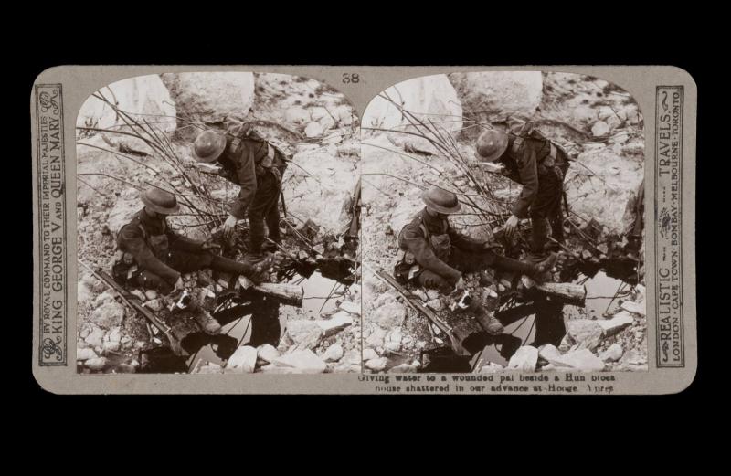 Giving water to a wounded pal beside a Hun blockhouse shattered in our advances at Hooge, Ypres. From the box The Great War