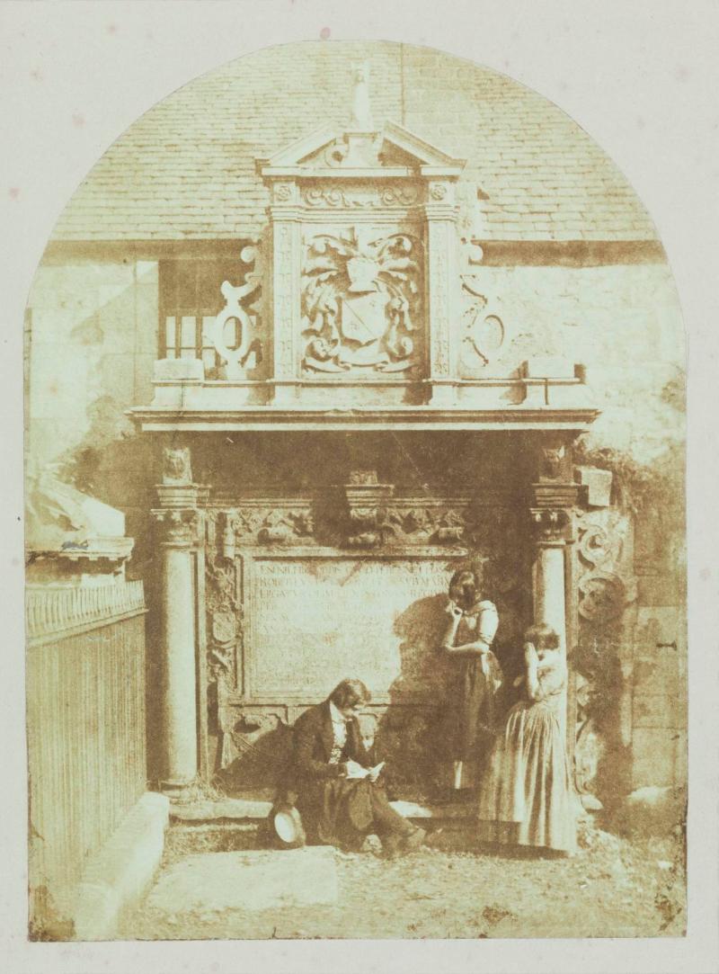 D.O. Hill sittande med ett skissblock vid Sir Robert Dennistouns grav, Greyfriars, Edinburgh [samt två kvinnor]