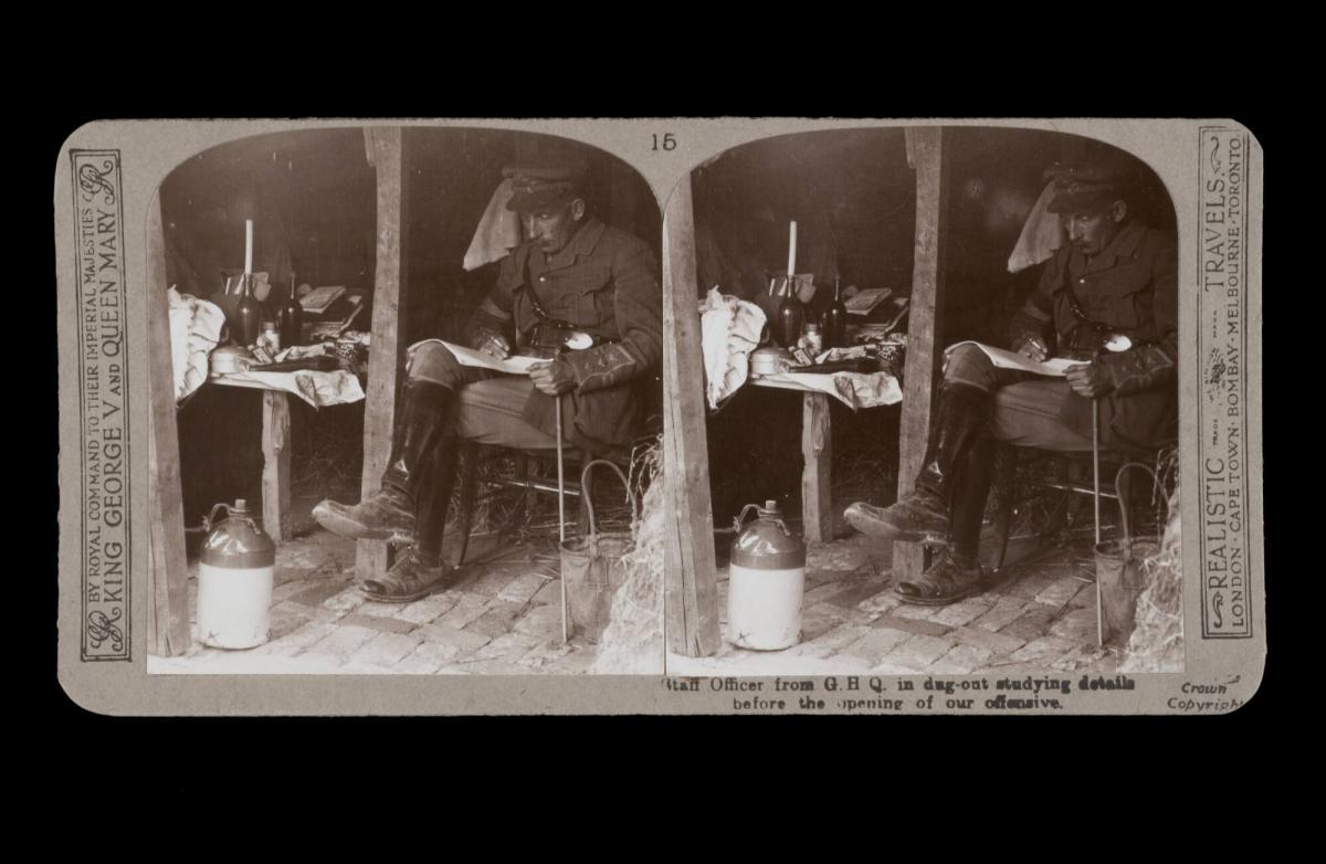 Staff Officer from G.H.Q. in dug-out studying details before the opening of our offensive. From the box The Great War